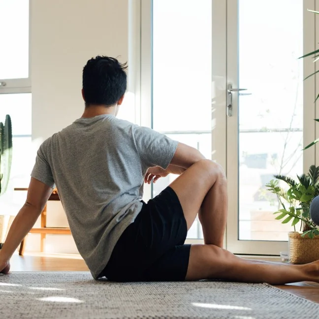 Vue arrière d'un jeune homme pratiquant une posture de yoga pour prévenir les douleurs lombaires