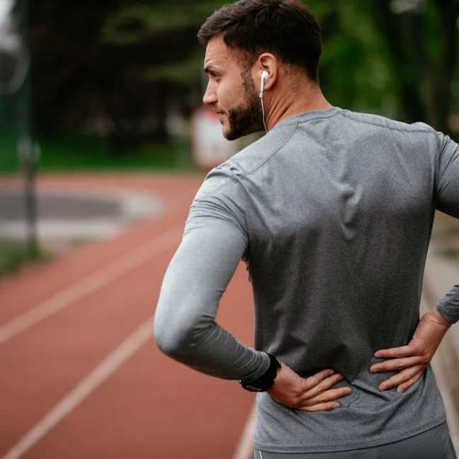 Homme souffrant de douleurs lombaires après avoir fait de l'exercice sur une piste de course à pied