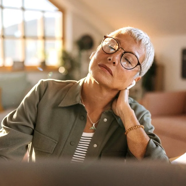 Femme s'étirant le cou pour soulager la tension musculaire tout en travaillant sur son ordinateur portable dans son bureau à domicile