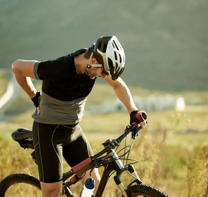 Homme ressentant des douleurs lombaires lors d'une promenade à vélo à la campagne