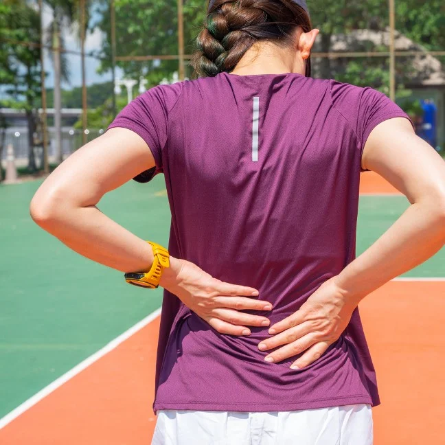 Femme souffrant de douleurs lombaires après avoir joué au tennis